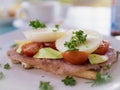 Open sandwich with two poached eggs, tomato, avocado, bacon, parsley and toast