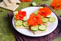 Open sandwiches with crisp bread, butter, fresh cucumber slices and nasturtium flowers on a white plate on an olive concrete Royalty Free Stock Photo