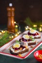 Open sandwiches smorrebroda on rye bread with marinated beetroot, cream cheese, herring and quail egg in Christmas style on a Royalty Free Stock Photo