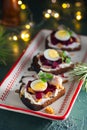 Open sandwiches smorrebroda on rye bread with marinated beetroot, cream cheese, herring and quail egg in Christmas style on a Royalty Free Stock Photo