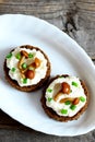 Open sandwiches with soft cheese, chanterelle mushrooms and green onions on a plate on vintage wooden background