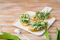 Open sandwiches with spring salad of wild garlic and boiled eggs on a white ceramic board on a wooden background. Using wild