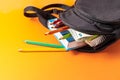 Open school backpack on an orange background. Books, a notebook and pencils are sticking out of an open school backpack Royalty Free Stock Photo