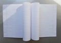 Open school notebook with pen on a gray desk with sun rays from the window. A blank, white sheet of notebook for writing. Royalty Free Stock Photo