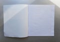 Open school notebook with pen on a gray desk with sun rays from the window. A blank, white sheet of notebook for writing. Royalty Free Stock Photo