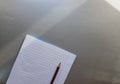 Open school notebook with pen on a gray desk with sun rays from the window. A blank, white sheet of notebook for writing. Royalty Free Stock Photo