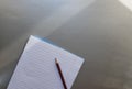 Open school notebook with pen on a gray desk with sun rays from the window. A blank, white sheet of notebook for writing. Royalty Free Stock Photo