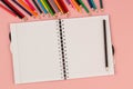 Open school squared notebook and pencils on the pink background. Top view Royalty Free Stock Photo