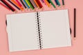 Open school squared notebook and pencils on the pink background. Top view Royalty Free Stock Photo