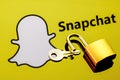 An open security lock and key on the background of the Snapchat instant messaging service logo in the mirror reflection