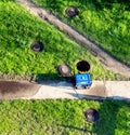 An open sewer well near which there is a gas generator on the grass. The concept of repair and maintenance of inspection