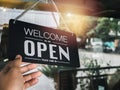 Open sign board with white text on black vintage wooden sign `Welcome we are open please come in` hanging on the glass door. Royalty Free Stock Photo