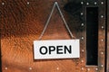 Open sign broad hanging on the door in cafe with Grunge vintage rusty metal plate texture background. Business service and food c