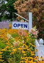 Open sign with flowers and a white pickett fence