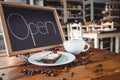 Open signboard with slice of cake and coffee cup on a table Royalty Free Stock Photo