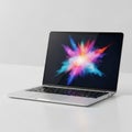 Open Silver Laptop Displaying a Colorful Abstract Explosion of Light on a White Surface Royalty Free Stock Photo