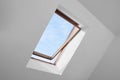 Open skylight roof window and lamps on slanted ceiling in attic room, low angle view Royalty Free Stock Photo
