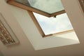 Open skylight roof window on slanted ceiling in attic room, low angle view Royalty Free Stock Photo