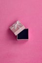 Open small gift box in pink with a small bow lies on a blanket of soft and furry light pink fleece fabric. Packing for a gift to y Royalty Free Stock Photo