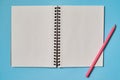 Open spiral blank notebook and pink pencil isolated on blue background, copy space for mockup. Still life, business, office. Royalty Free Stock Photo