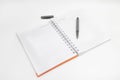 Open spiral-bound notebook with an orange cover, accompanied by a black pen, with copy space Royalty Free Stock Photo