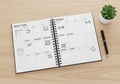 An open spiral-bound planner on a wooden desk displays a weekly layout with labeled days and Royalty Free Stock Photo