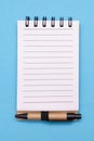 Open spiral lined paper notebook with small pen on blue background Royalty Free Stock Photo