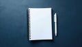 Open spiral notebook with blank white pages and a pen lie on dark blue textured surface. Ready for writing plans, notes, ideas, Royalty Free Stock Photo