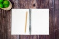 An open spiral sketchbook and a wooden pencil on wood table.