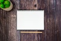 An open spiral sketchbook and a wooden pencil on wood table, decorate with a plant