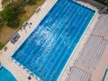 The open sports swimming pool glistened under the bright sun as people swimming in its inviting waters.