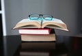 Open stack hardback books with glasses on wooden table. Education background