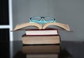 Open stack hardback books with glasses on wooden table. Education background