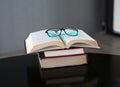 Open stack hardback books with glasses on wooden table. Education background