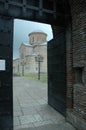 The open steel door of the gate leading to the ancient medieval temple. A brick wall enclosing a medieval church. Old Royalty Free Stock Photo