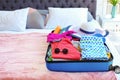 Open suitcase with beach clothes and accessories on bed Royalty Free Stock Photo