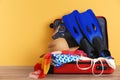 Open suitcase with clothing and swimming accessories on table.