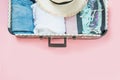 Open suitcase with female clothes for trip on pastel pink. Top view with copy space. Summer concept travel. Royalty Free Stock Photo