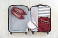 Open suitcase with female clothing, shoes