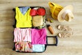 Open suitcase fully packed with folded women`s clothing and accessories on the floor. Woman packing for tropical vacation concept Royalty Free Stock Photo