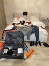 Open Suitcase lay on floor with mess on bed and around room. Packing or unpacking luggage. Royalty Free Stock Photo