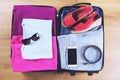 Open suitcase packed for travelling, on wooden floor top view, close up. Travel bag concept Royalty Free Stock Photo