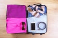 Open suitcase packed for travelling, on wooden floor top view, close up. Travel bag concept Royalty Free Stock Photo