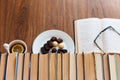 Open textbook, glasses, cup of tea and chocolate candies on white plate, stack of old book on wooden table, education concept