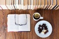 Open textbook, glasses, cup of tea and chocolate candies on white plate, stack of old book on wooden table, education concept Royalty Free Stock Photo