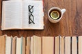 Open textbook, glasses, cup of tea and stack of old book on wooden table, education concept background, many books piles with copy