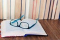 Open textbook, glasses, stack of old book on wooden table, education concept background, many books piles with copy space for text