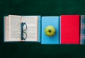 Open textbook  pile of books in colorful covers and apple with blackboard background. Distance home education. Back to school Royalty Free Stock Photo