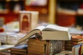 Open thick book on pile of books in book store or in library, selective focus, blurred background. Education, reading Royalty Free Stock Photo