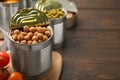 Open tin can with chickpeas and tomatoes on wooden table, closeup. Space for text Royalty Free Stock Photo